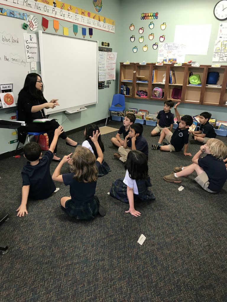Children sitting on the floor listening to their teacher